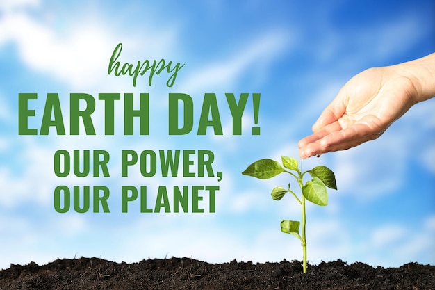 Earth Day green sprout and hand with water on clear sky background with text