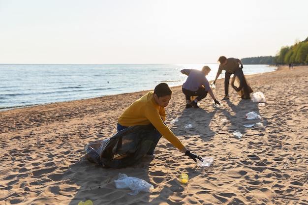 Earth day volunteers activists collects garbage cleaning of beach coastal zone woman and mans puts