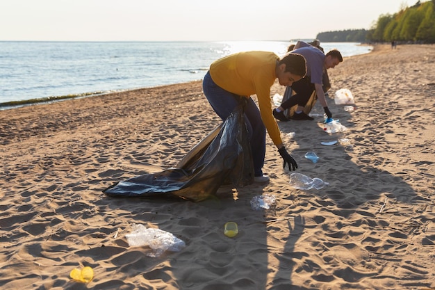 Photo earth day volunteers activists collects garbage cleaning of beach coastal zone woman and mans puts