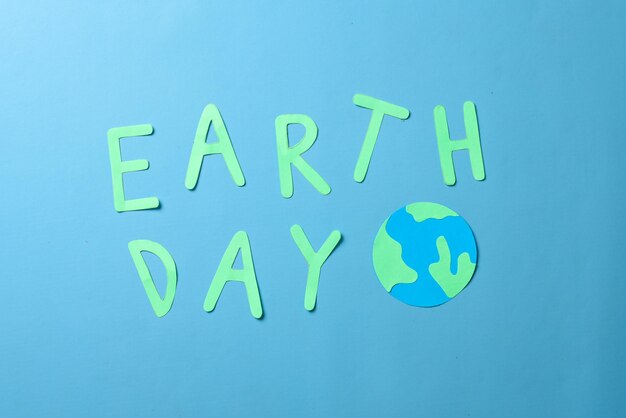 Earth day woorden en globe gemaakt van papier geïsoleerd op blauwe achtergrond. Wereld aarde dag concept.