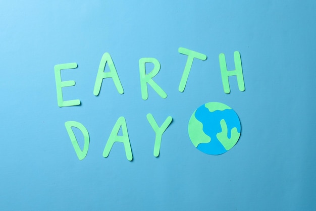 Earth day words and globe made from paper isolated on blue background. World earth day concept.