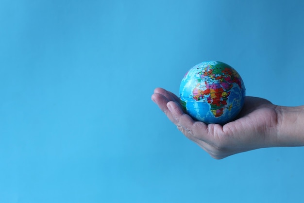 Globo terrestre in mani umane su sfondo blu per la giornata mondiale della terra.