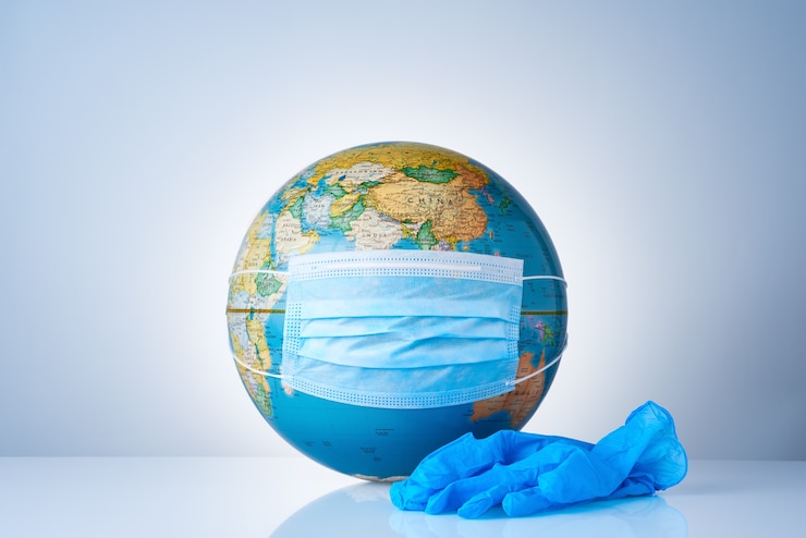 Foto earth globe met medisch masker naast een paar chirurgische handschoenen