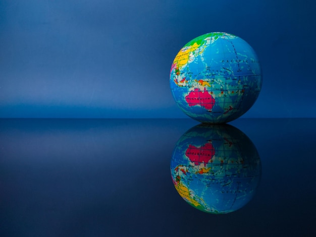 Earth globe with reflection on a black acrylic board with copy space