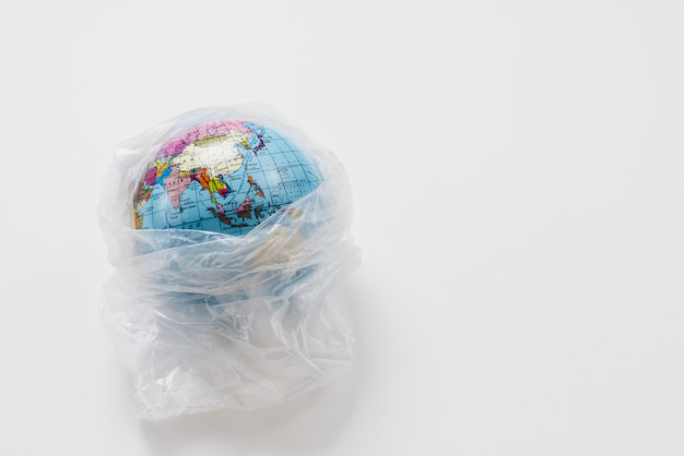 Foto globo terrestre avvolto in un sacchetto di plastica spazzatura