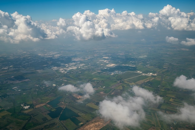 Фото Земной пейзаж рассматривается с самолета. земля под белыми облаками с высоты птичьего полета.