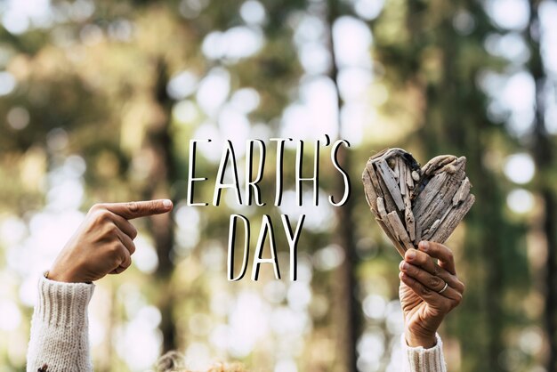 Earth's day-sms-bericht met menselijke mensenhanden die een houten haard en groene, mooie onscherpe houtdennenbomen nemen