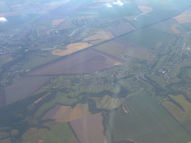 The earth's surface was taken from the height of the aircraft. Below - land parcels divided into parts against the background of small clouds