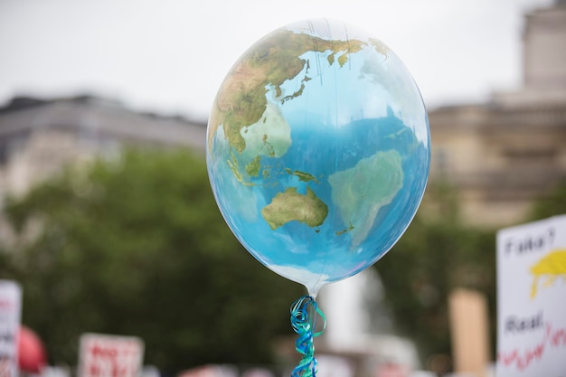 Воздушный шар в форме земли, плавающий на веревочной концепции климата и окружающей среды