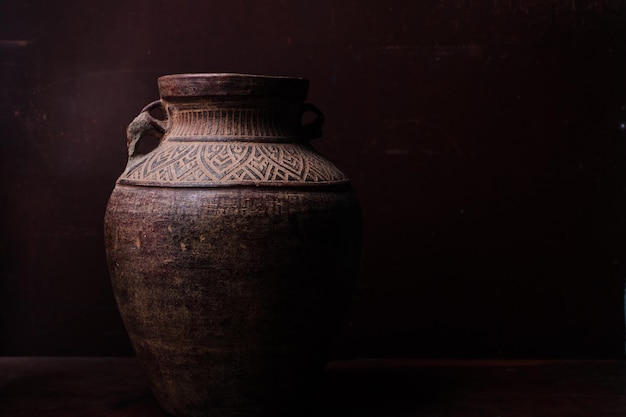 Earthenware jug standing on dark room or tiles with copyspace