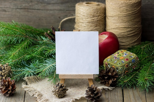 Easel with sheet of paper and fir branches with twine