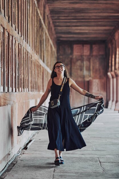 East asian woman in black dress dancing with translucent scarf among columns of ancient temple