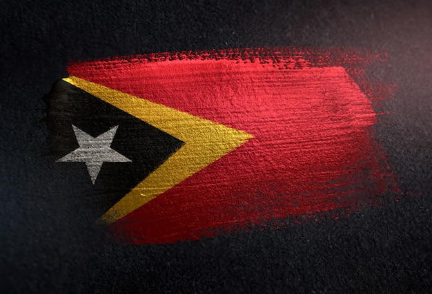 Флаг Восточного Тимора, выполненный из металлической кисти, на темной стене Гранж