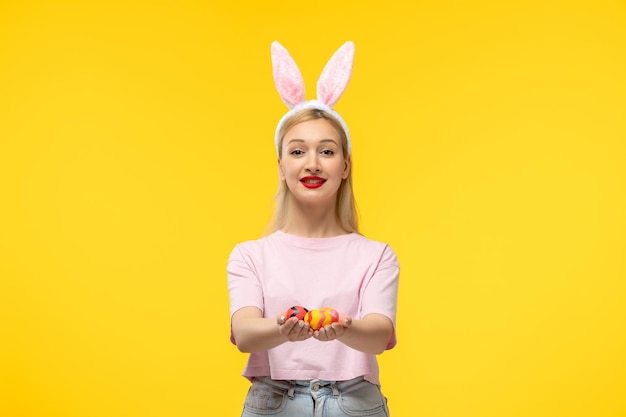 Easter adorable pretty young blonde girl with bunny ears happily giving easter eggs