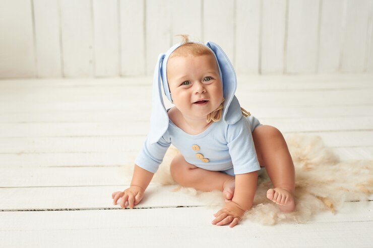 Easter Baby boy sitting on crib. Easter bunny. Happy Baby