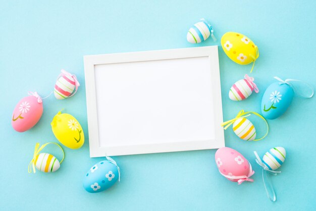 Easter background on blue colored easter eggs with decorations and white frame for text flat lay with copy space