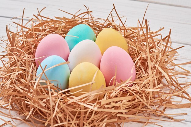 Easter background. Colorful easter eggs in paper nest on a white background, close up