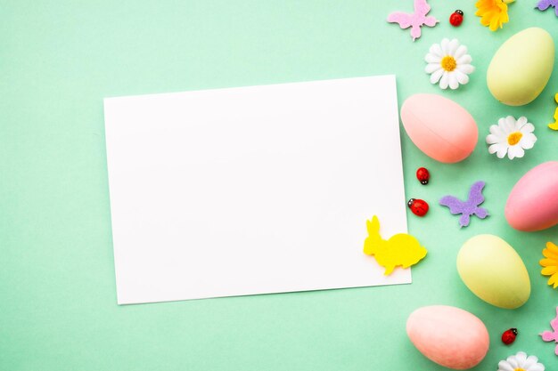 Easter background eggs rabbit spring flowers and butterfly flat lay mock up at green background