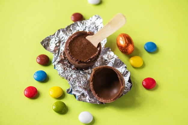 녹색 배경에 크림 충전물과 다채로운 사탕이 있는 초콜릿 부활절 달걀의 부활절 배경 오버헤드 보기