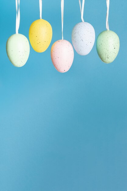 Easter background Hanging eggs on blue vertical banner with copy space