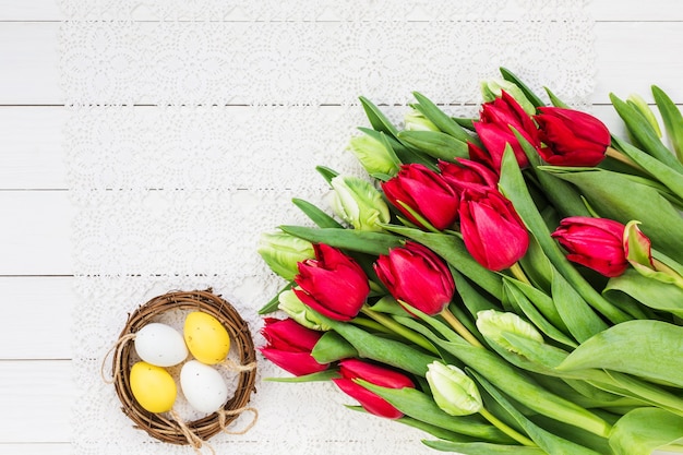 Easter background, white and red tulips, decorative Easter eggs. Copy space, top view