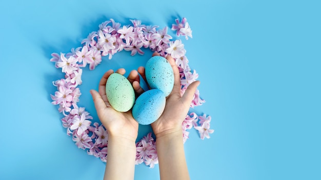 Фото Пасха фон с синие пасхальные яйца в гнезде из весенних цветов. вид сверху с копией пространства.