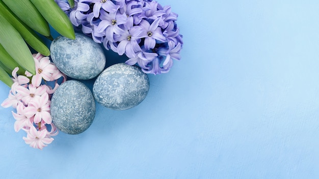 Easter background with blue eggs and spring flowers. Top view with copy space.