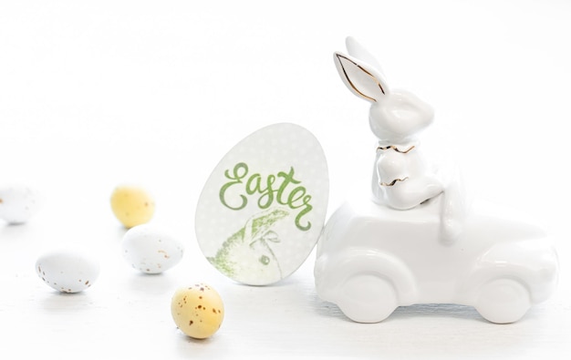 Easter background with a ceramic hare in the car and eggs on a white background