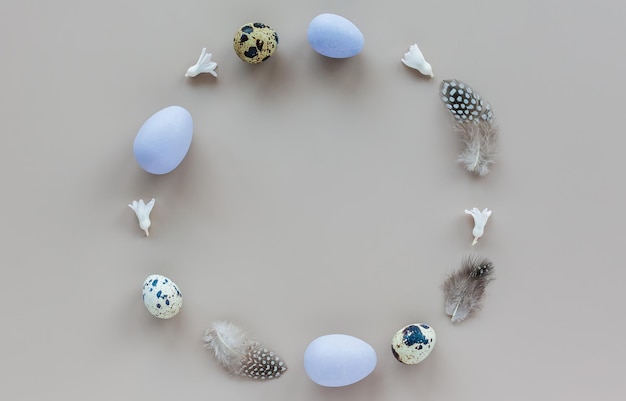 Easter background with a circle made of easter eggs and feathers on a pastel colored background