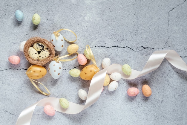 Easter background with colorful Easter eggs with bird's nest and pink satin ribbon with copy space