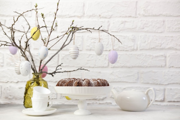 イースターの背景に卵、春の枝、白いレンガの背景にイースターパイとハッピー イースター テーブル設定休日の背景