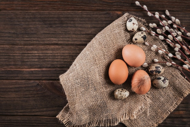 Easter background with natural color eggs pussy willow branches and brown feathers on beige background Free space for text