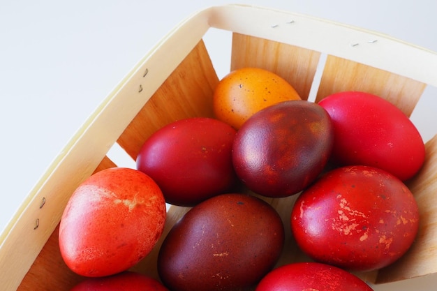 Easter basket closeup with colorful eggs Boiled chicken eggs with red orange yellow and brown shells dyed with onion peel according to a traditional recipe White festive background