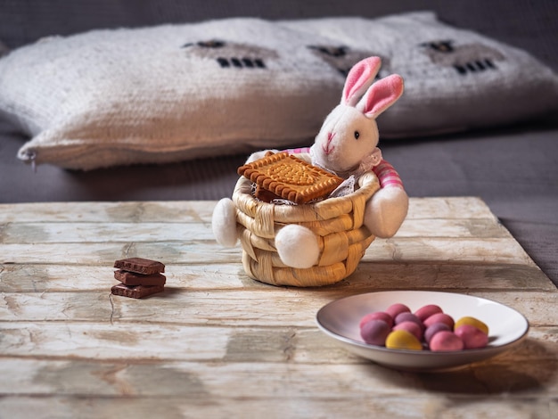 Фото Пасхальная корзина с фигуркой кролика с многоцветными шоколадными яйцами на легком подносе