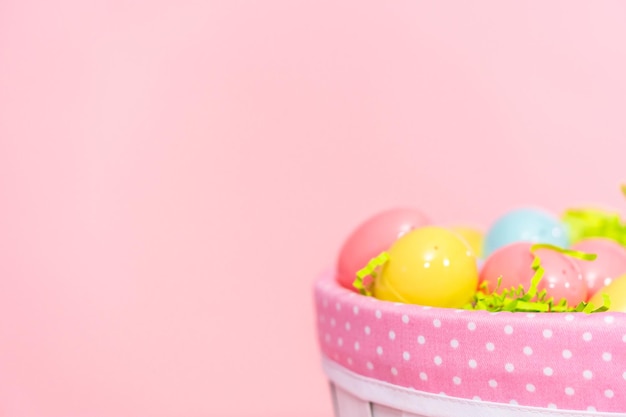 Easter basket with easter eggs on a pink background.