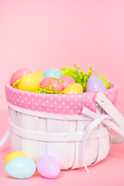 Easter basket with easter eggs on a pink background.