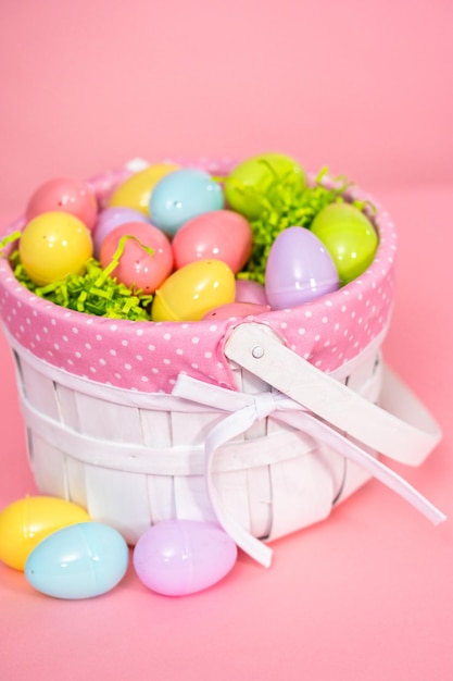 Easter basket with easter eggs on a pink background.