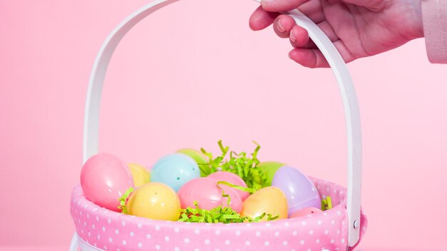 Easter basket with plastic eggs on a pink background.