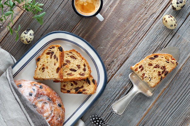 Easter Bread (Osterbrot in German). Top view of traditional fruity bread on rustic wood  with fresh leaves and quail eggs