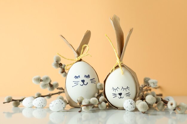 Easter bunnies made of eggs, quail eggs and catkins against beige background