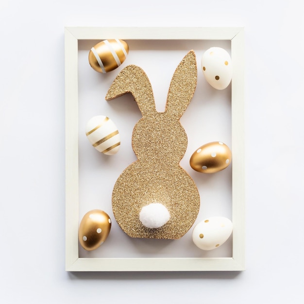 Фото Пасхальный кролик и золотые яйца на белом фоне в рамке счастливой пасхи минимальная концепция поздравительной открытки мягкий выборочный фокус