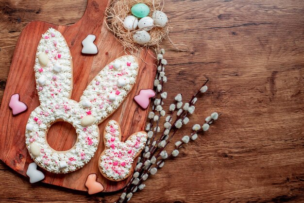 Easter bunny cookies on a wooden board with eggs and flowers