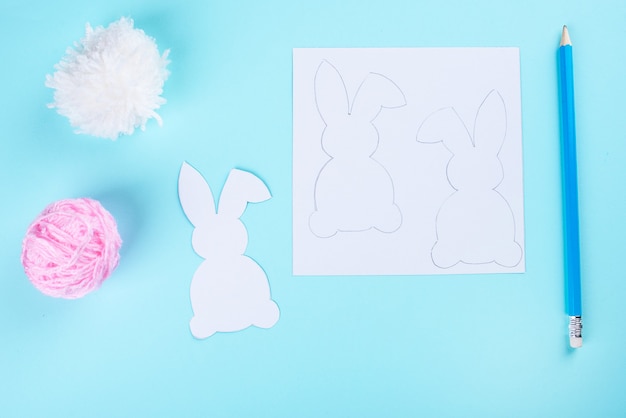 Photo easter bunny decoration paper cut background. diy holiday handicraft garland of colorful rabbits and craft tools.