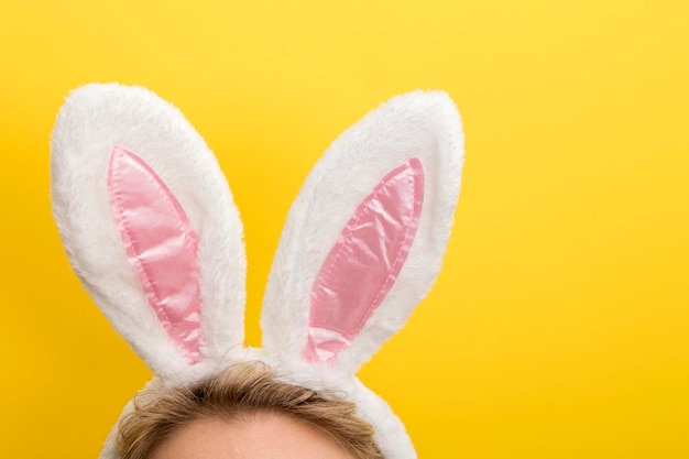 Easter bunny ears female wearing white bunny ears costume\
against a bright yellow background