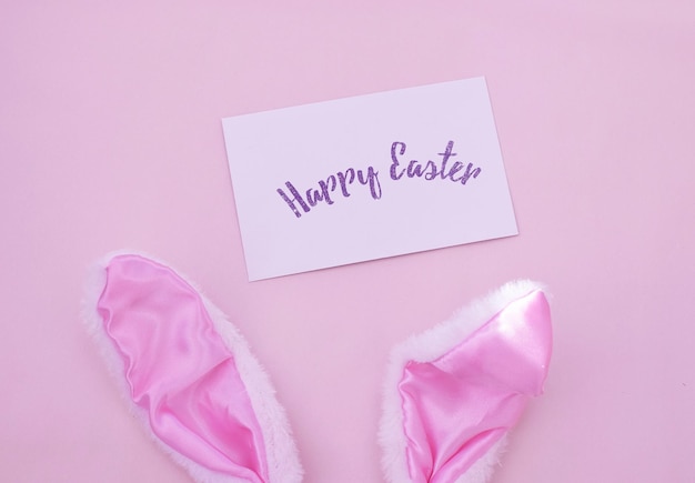 Easter bunny ears on a pink background. Postcard with text Happy Easter.