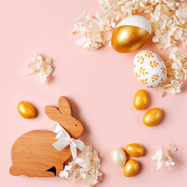 Foto coniglietto di pasqua e uova d'oro con caramelle e fiori su sfondo rosa pastello concetto di vacanza buona pasqua cardx9