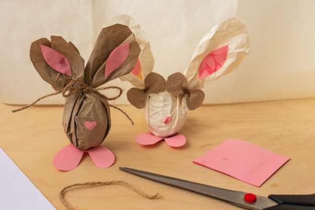 Easter bunny made of a brown chicken egg and craft paper in the hands of a girl, close-up