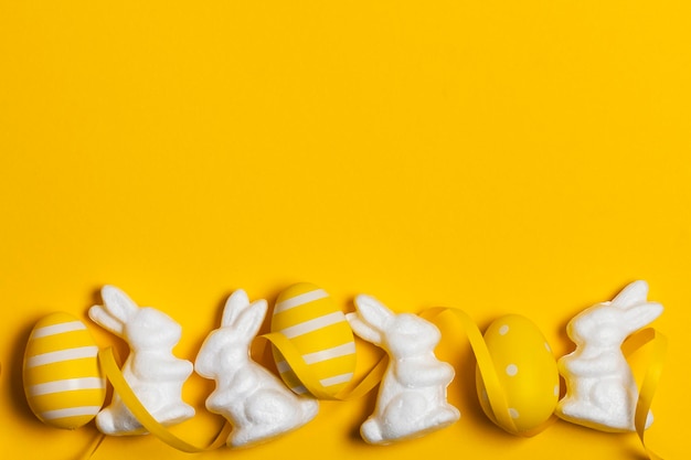 Easter bunny rabbit and eggs on a bright yellow background