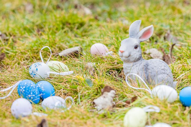 Easter bunny sitting among multicolored eggs in grass Easter bunny and Easter eggs on green grass