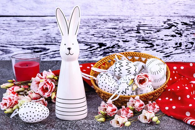 Photo easter bunny white eggs with black polka dots in a basket a red shawl a candle eustoma flowers